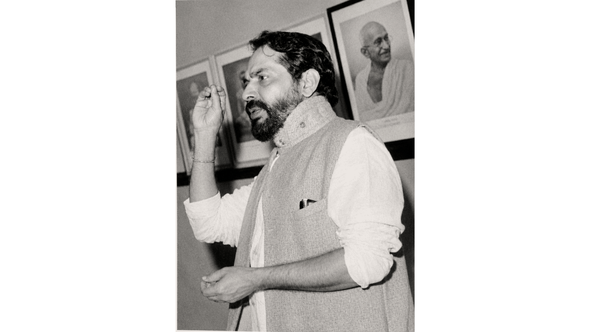 Archival photograph — At work, beneath a portrait of Mahatma Gandhi